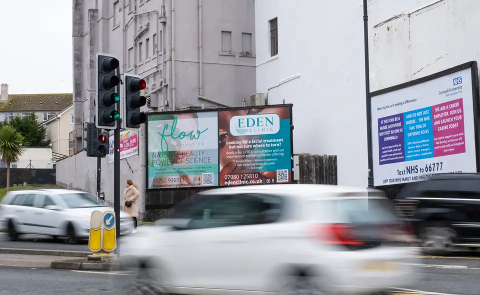 Billboards on Fore Street, Plymouth, with traffic at the junction